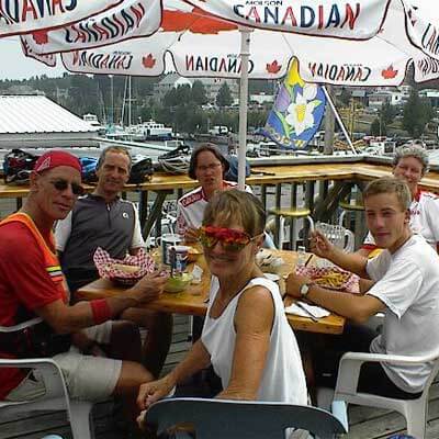 Cyclists in costumes on deck having meal